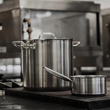 a pot and pan on a stove in a commercial kitchen