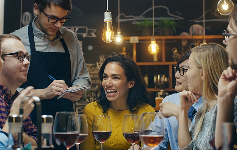 a happy group of friends and a waiter inside a restaurant